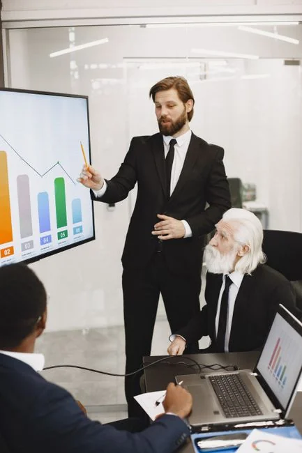 Hands using smartphone beside laptop with stock charts, showcasing digital trading.