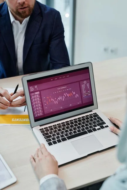 Person analyzes stock data with a smartphone and laptop, indoors.